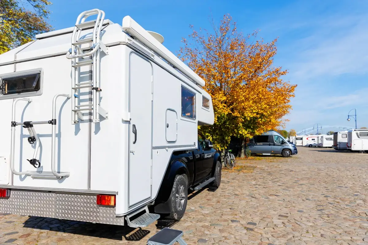 White slide-in truck camper mounted on the bed of a black pickup truck